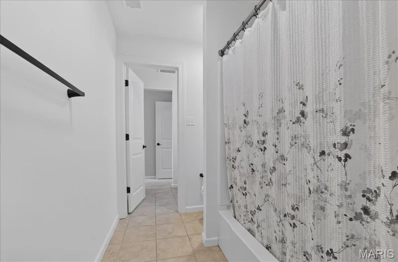 Bathroom featuring a white bathtub, light tile flooring, and a towel bar with a matte black finish — 302 Oak Stand Court, Chesterfield, MO 63005
