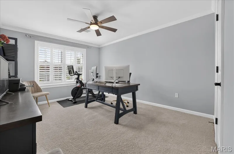 Carpeted room featuring a ceiling fan with integrated lighting, crown molding, and light gray walls — 302 Oak Stand Court, Chesterfield, MO 63005