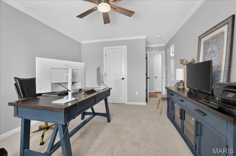 Carpeted interior space featuring light gray walls, white trim, and a ceiling fan with integrated lighting — 302 Oak Stand Court, Chesterfield, MO 63005