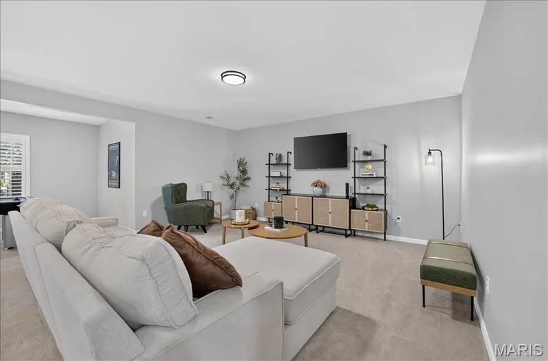 Spacious room featuring light gray walls, neutral carpeting, a large window with white plantation shutters, and a modern ceiling light fixture — 302 Oak Stand Court, Chesterfield, MO 63005