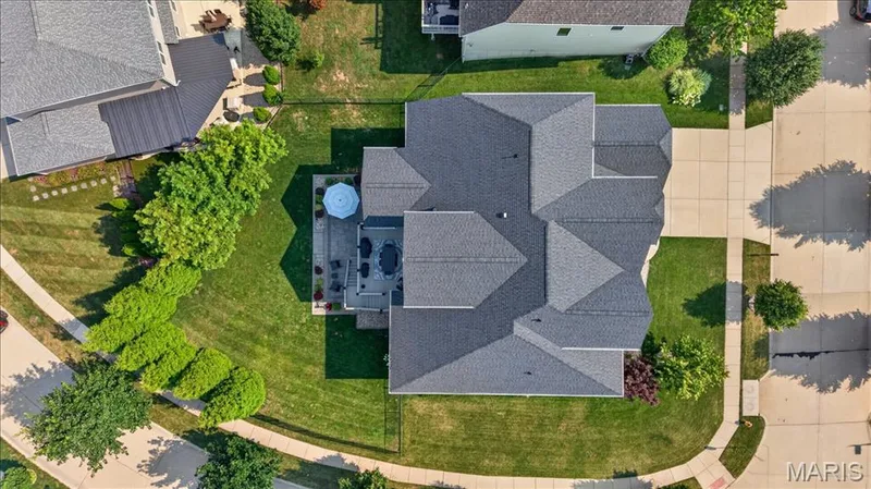 Expansive property featuring a multi-gabled roofline, concrete driveway, and a spacious rear patio — 302 Oak Stand Court, Chesterfield, MO 63005