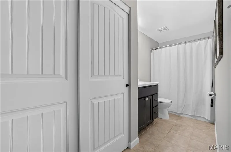 Bathroom featuring a dark wood vanity with a white countertop, toilet, and tiled flooring — 302 Oak Stand Court, Chesterfield, MO 63005