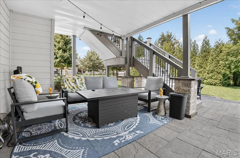 Covered patio featuring string lighting and a stone-look paver floor — 302 Oak Stand Court, Chesterfield, MO 63005