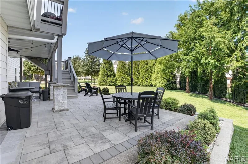Spacious paver patio with a bordering stone knee wall and mature landscaping — 302 Oak Stand Court, Chesterfield, MO 63005