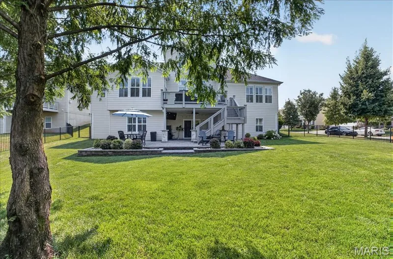 Expansive backyard featuring a large green lawn, a stone patio, and a multi-level wood deck — 302 Oak Stand Court, Chesterfield, MO 63005
