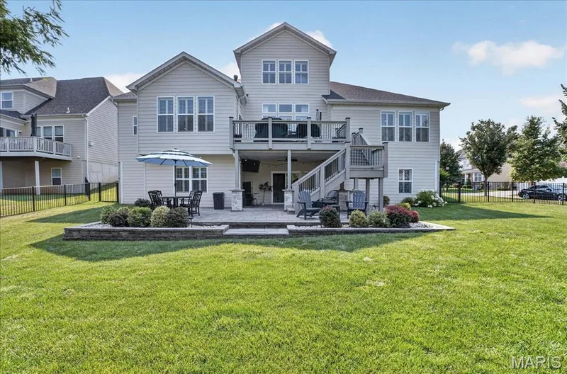 Rear exterior featuring a two-story deck, lower-level patio with stone pavers, and a spacious lawn — 302 Oak Stand Court, Chesterfield, MO 63005