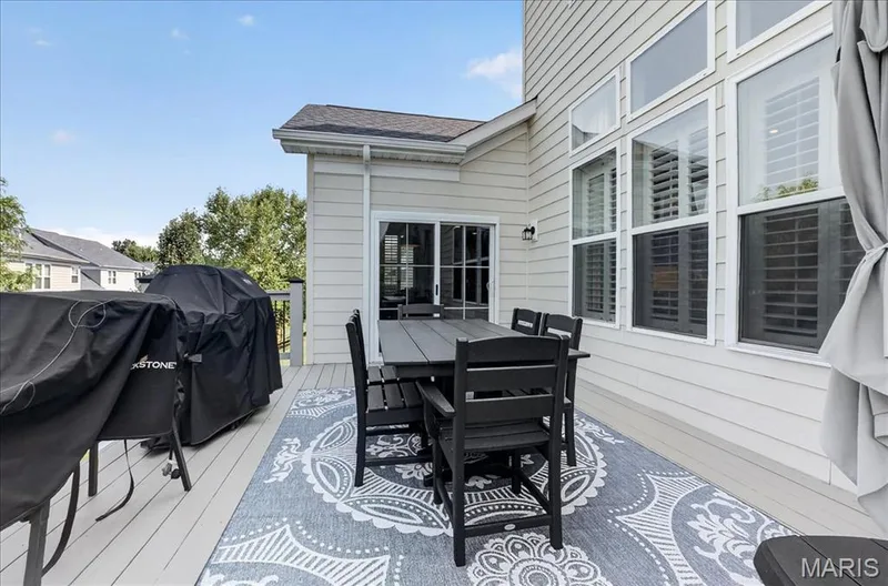 Expansive outdoor deck featuring wood-finish flooring, a full-lite sliding glass door, and multiple large windows with interior shutters — 302 Oak Stand Court, Chesterfield, MO 63005