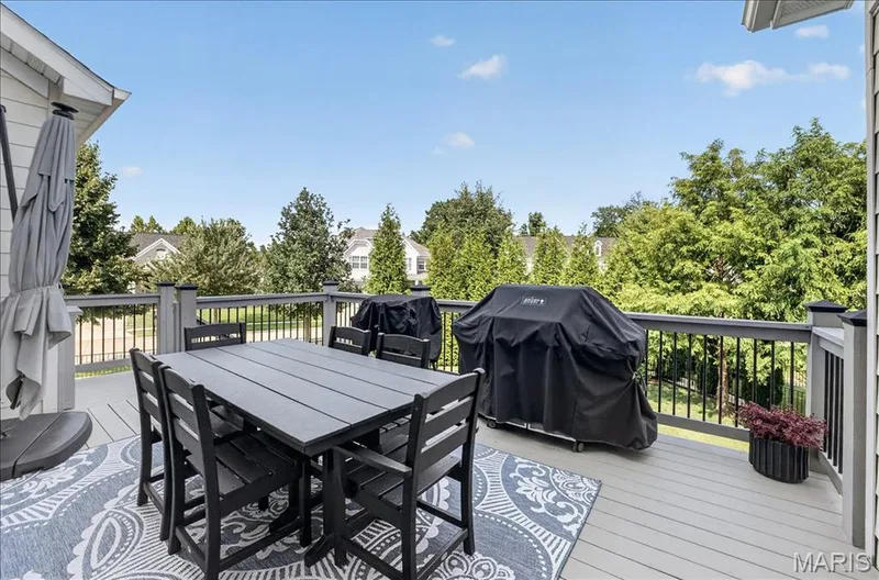 Expansive outdoor deck featuring composite decking, dark gray railing with black balusters, and a surrounding of mature trees — 302 Oak Stand Court, Chesterfield, MO 63005