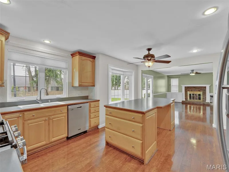 A great view of the kitchen, with windows over the kitchen sink, large bay window, a huge functional island, room for a  kitchen table, and the family room beyond. — 34 Shadow Creek Drive, St Peters, MO 63376
