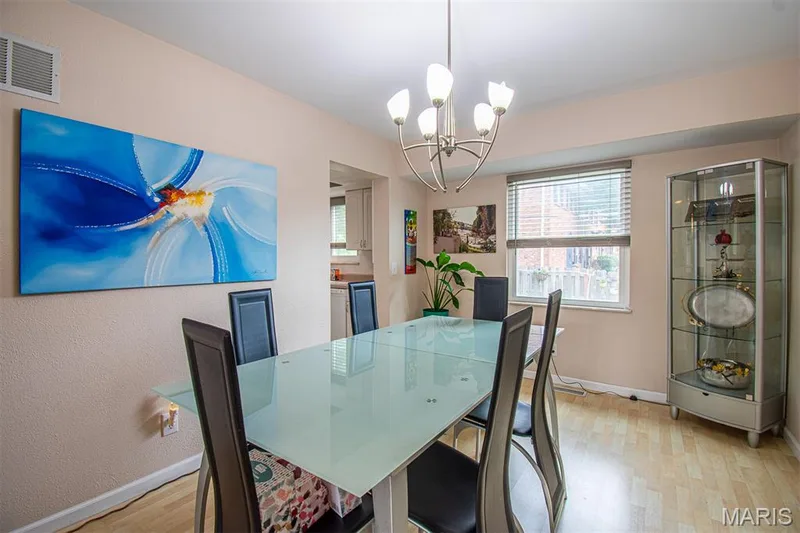 DINING ROOM – Opens to Living Room & Kitchen. Illuminated dining area featuring wood-finish flooring, a contemporary chandelier, and a window with horizontal blinds. — 13261 COCHERO Drive, Chesterfield, MO 63141