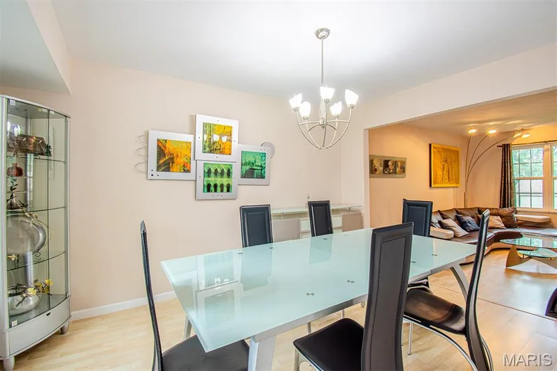DINING ROOM – Opens to Living Room & Kitchen. Dining area featuring light wood-finish flooring, a contemporary chandelier, and an open entryway to a living area — 13261 COCHERO Drive, Chesterfield, MO 63141