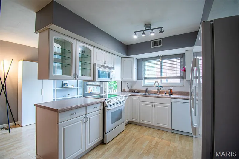 KITCHEN - Kitchen featuring light wood-finish flooring, white cabinetry, integrated stainless steel microwave, and white appliances — 13261 COCHERO Drive, Chesterfield, MO 63141