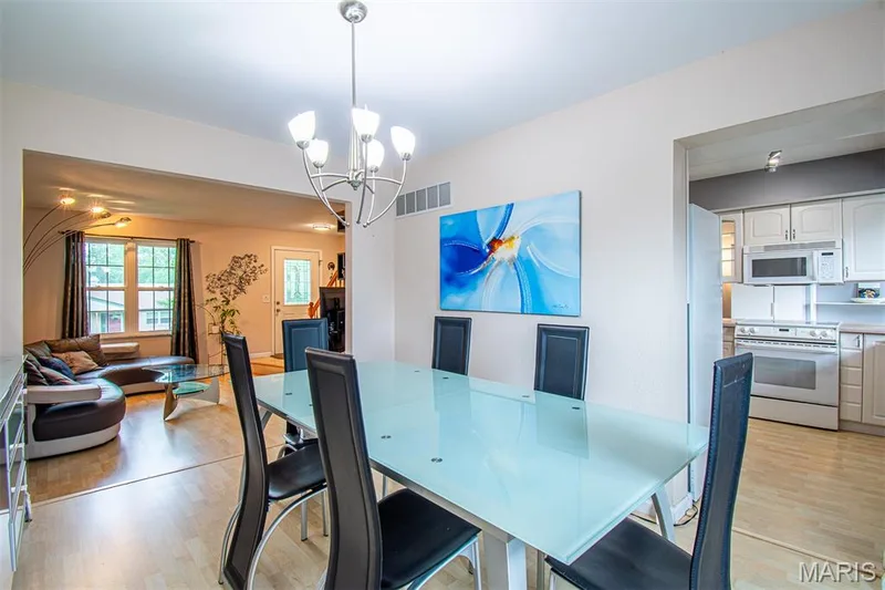 DINING ROOM – Opens to Living Room & Kitchen. Dining area with a five-light chandelier, presenting wood-finish flooring — 13261 COCHERO Drive, Chesterfield, MO 63141