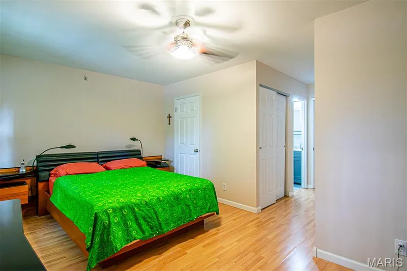 PRIMARY BEDROOM – With Walk-in & Additional Closet, and Ensuite Bathroom with Shower. Bedroom featuring light wood-finish flooring, a ceiling fan with integrated lighting, and a white paneled door — 13261 COCHERO Drive, Chesterfield, MO 63141
