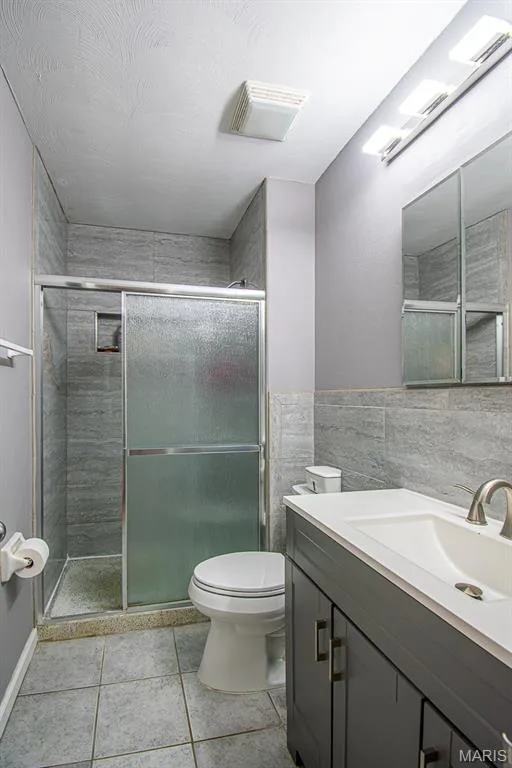 PRIMARY BATHROOM – Beautifully Remodeled & featuring a glass-enclosed shower with tile surround, a built-in shower niche, a dark gray vanity with an integrated sink, a brushed nickel faucet, and a wall-mounted medicine cabinet with mirrored doors — 13261 COCHERO Drive, Chesterfield, MO 63141