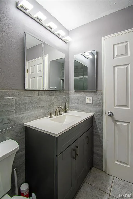 PRIMARY BATHROOM – Beautifully Remodeled & featuring a glass-enclosed shower with tile surround, a built-in shower niche, a dark gray vanity with an integrated sink, a brushed nickel faucet, and a wall-mounted medicine cabinet with mirrored doors — 13261 COCHERO Drive, Chesterfield, MO 63141