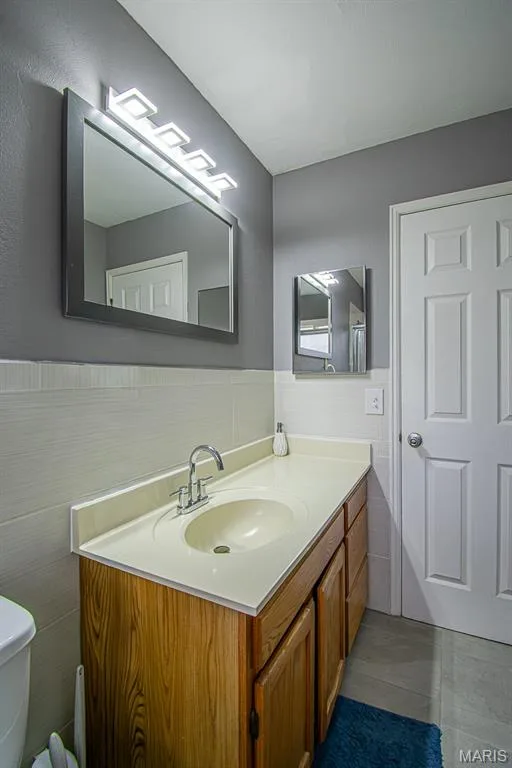 GUEST BATHROOM - Bathroom vanity featuring a wood-finish cabinet, integrated sink, and light-toned countertop — 13261 COCHERO Drive, Chesterfield, MO 63141