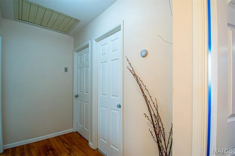 UPPER-LEVEL LOFT - Hallway featuring wood-finish flooring, two white panel doors, and a ceiling access panel — 13261 COCHERO Drive, Chesterfield, MO 63141