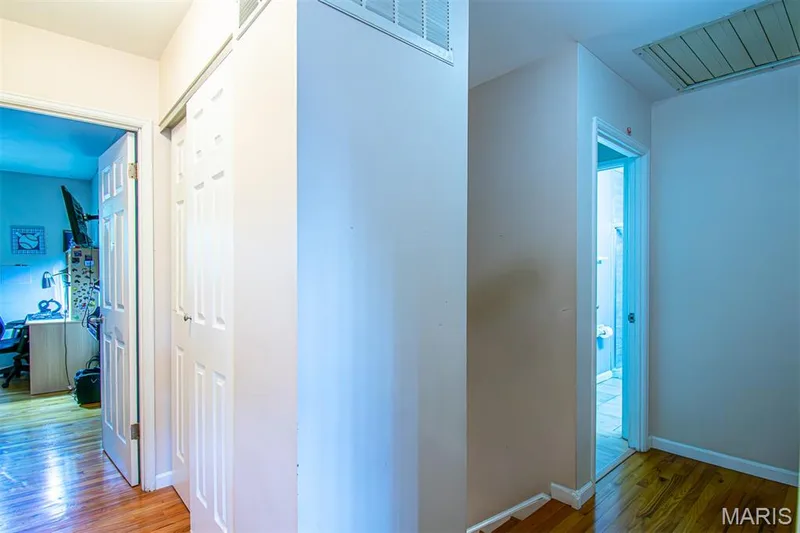 UPPER-LEVEL LOFT - Hallway featuring wood-finish flooring, two white panel doors, and a ceiling access panel — 13261 COCHERO Drive, Chesterfield, MO 63141