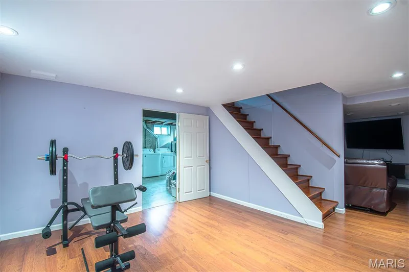 LOWER-LEVEL REC/R # 1 - featuring wood-finish flooring, recessed lighting, and a white paneled door , entrance to large storage/utility/laundry room area. — 13261 COCHERO Drive, Chesterfield, MO 63141