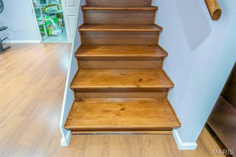 LOWER-LEVEL - Staircase with natural wood treads and risers, complemented by a wood-finish handrail and baseboard trim — 13261 COCHERO Drive, Chesterfield, MO 63141