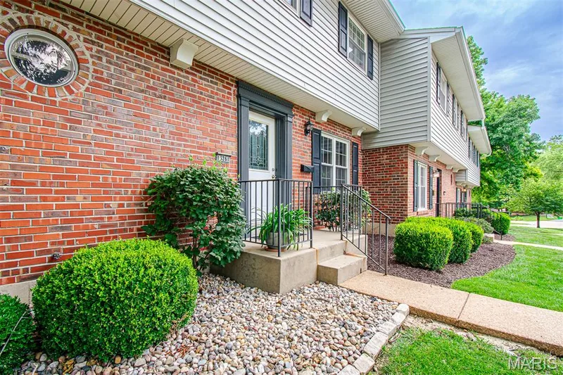 MAIN ENTRANCE – Front porch & landscaping . Brick and siding exterior featuring a round architectural window and a white entry door with decorative glass — 13261 COCHERO Drive, Chesterfield, MO 63141