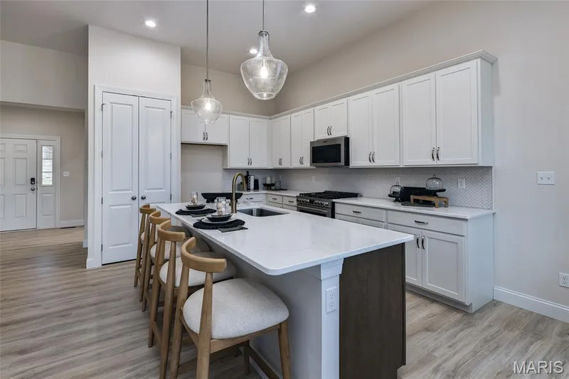 Kitchen with a view of the kitchen island and custom two-tone cabinets and stainless steel gas appliances — 401 Farmhouse Drive, O'Fallon, MO 63385