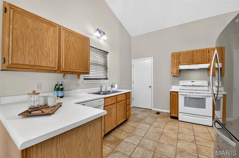 Bright kitchen with ceramic tile and yes....the fridge does stay!  Door in the distance leads to the attached 2 car garage. — 582 Prentice Drive, St Peters, MO 63376