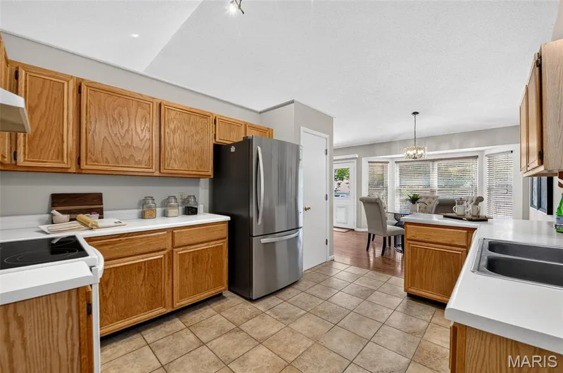 View of kitchen toward the rear of the home.  Note the door to the right of the fridge is a designated pantry. — 582 Prentice Drive, St Peters, MO 63376
