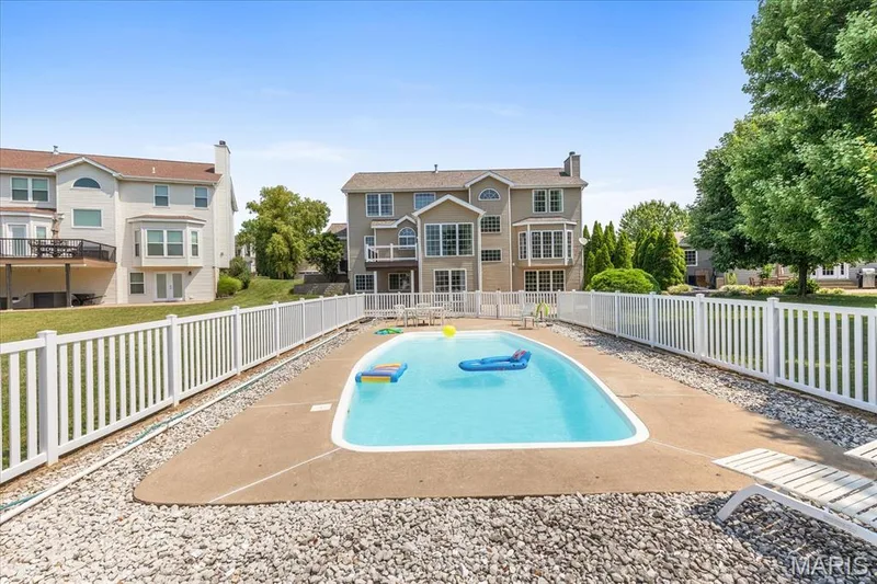 Inground, salt-water pool framed by concrete sundeck, new white vinyl privacy fence with safety lock, and open views toward the rear elevation of the home. — 354 Buckington Street, St Peters, MO 63376