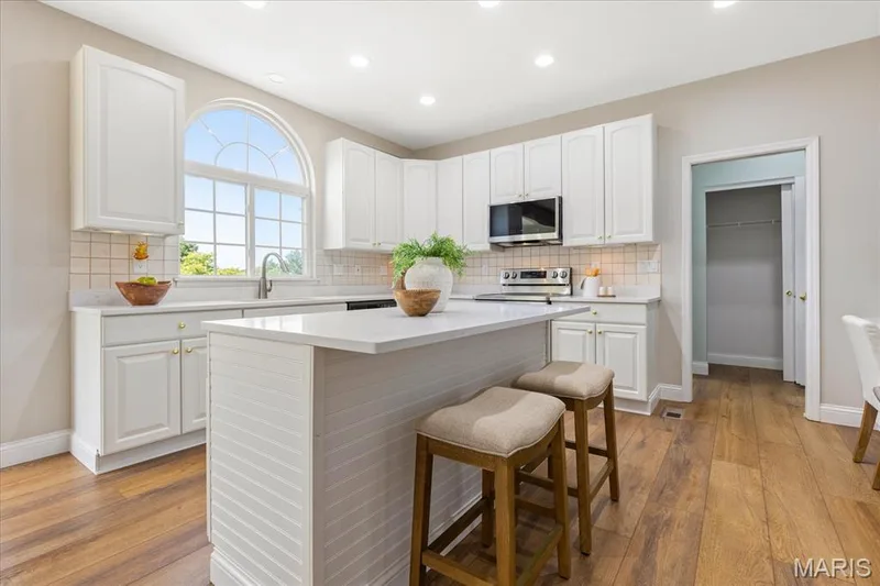 Cook and entertain with ease in this gourmet kitchen. This kitchen features brand-new quartz countertops, a center island with breakfast bar, stainless steel appliances, and a beautiful arched window overlooking the background. — 354 Buckington Street, St Peters, MO 63376