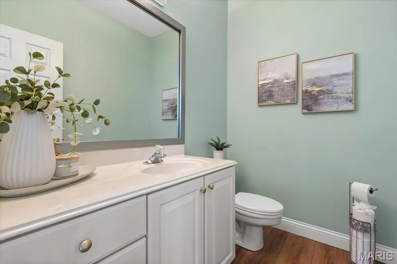 Main-floor, large powder room featuring an oversized white vanity and a soothing color palette. — 354 Buckington Street, St Peters, MO 63376