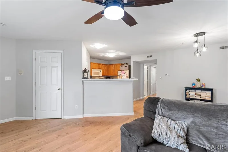 Living area featuring wood-finish flooring, light gray wall tones, and a ceiling fan with integrated lighting — 640 Homerun Drive #37N, O'Fallon, MO 63366