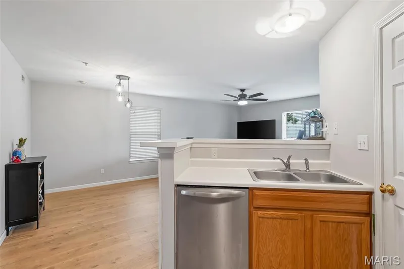 Kitchen counter with a stainless steel double basin sink, chrome faucet, and wood cabinetry — 640 Homerun Drive #37N, O'Fallon, MO 63366