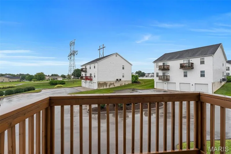 Wood-finish railing framing a residential landscape with a paved drive and green spaces — 640 Homerun Drive #37N, O'Fallon, MO 63366
