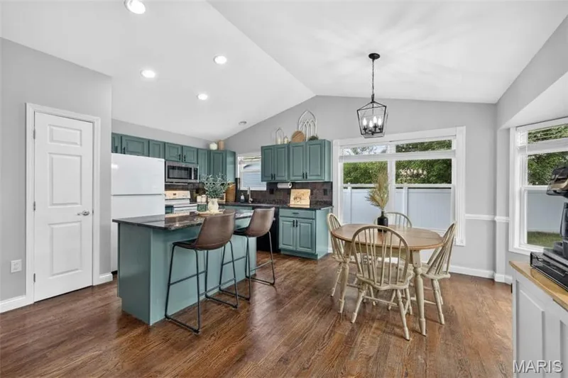 Wood-finish flooring, recessed lighting, vaulted ceiling, kitchen island with seating, and a pendant light fixture — 708 Woodland Ridge Drive, St Peters, MO 63376