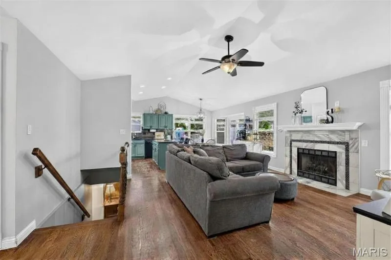 Expansive living area with wood-finish flooring, a vaulted ceiling, and a ceiling fan — 708 Woodland Ridge Drive, St Peters, MO 63376