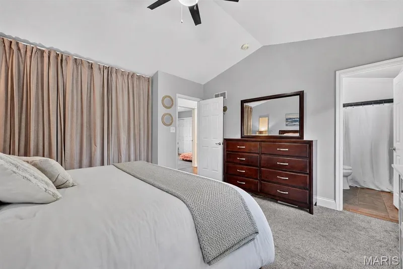 Vaulted ceiling with ceiling fan, wall-to-wall carpeting, and an ensuite bathroom featuring tile flooring — 708 Woodland Ridge Drive, St Peters, MO 63376