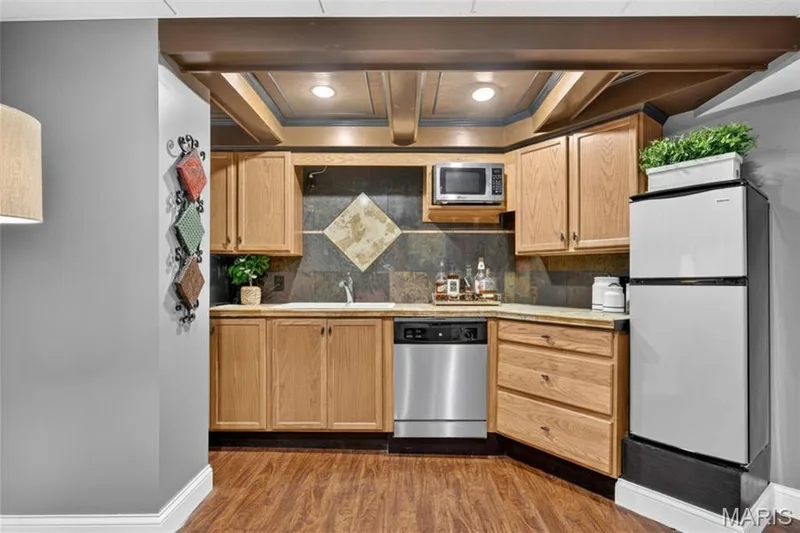 Compact kitchen area featuring wood-finish cabinetry, a stainless steel dishwasher, and a built-in microwave — 708 Woodland Ridge Drive, St Peters, MO 63376