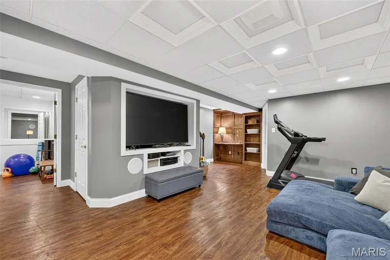 Integrated media wall with built-in shelving, wood-finish flooring, recessed lighting, drop ceiling, and built-in wood cabinetry with shelving — 708 Woodland Ridge Drive, St Peters, MO 63376