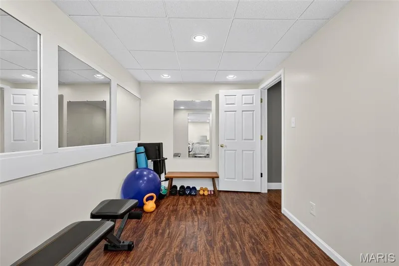 Recessed ceiling lighting, wood-finish flooring, drop ceiling, interior paneled door, and wall-mounted mirrors — 708 Woodland Ridge Drive, St Peters, MO 63376