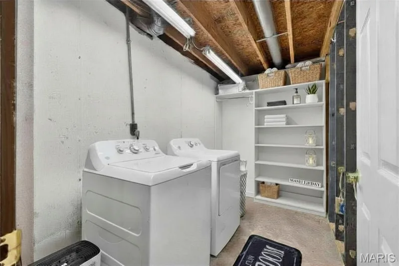 Laundry area featuring concrete flooring, exposed ceiling joists, white painted walls, and built-in shelving — 708 Woodland Ridge Drive, St Peters, MO 63376