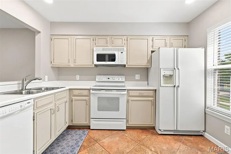 Kitchen featuring tiled flooring, white appliances, recessed lighting, double basin sink, and a window with blinds — 16561 Carriage View Court, Wildwood, MO 63040
