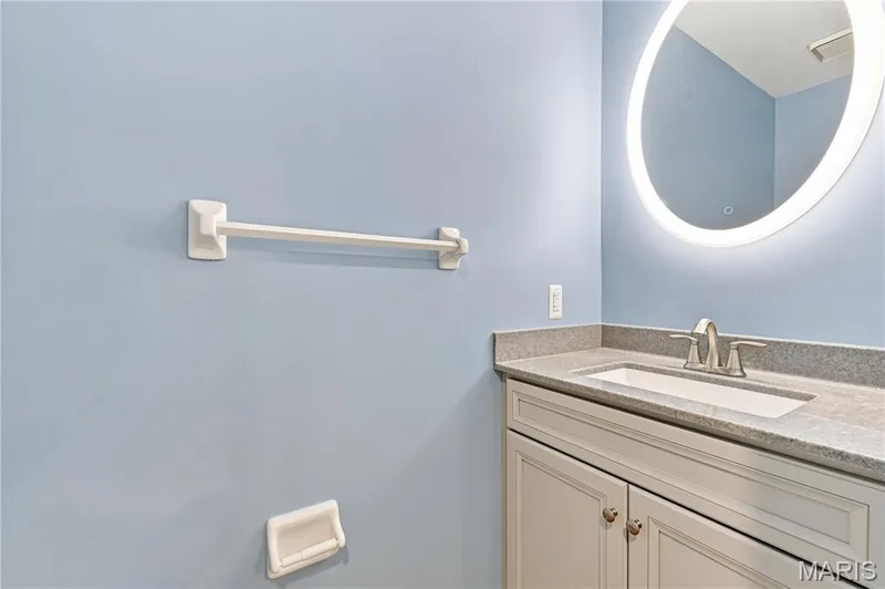 Vanity with shaker-style cabinetry, an integrated sink, and a speckled countertop — 16561 Carriage View Court, Wildwood, MO 63040