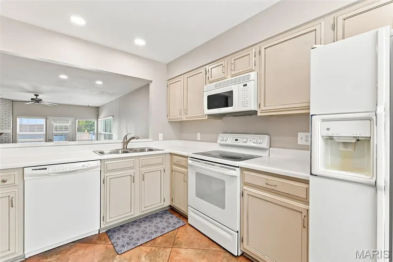 Kitchen featuring a pass-through window, recessed lighting, double basin sink, white appliances, and tiled flooring — 16561 Carriage View Court, Wildwood, MO 63040