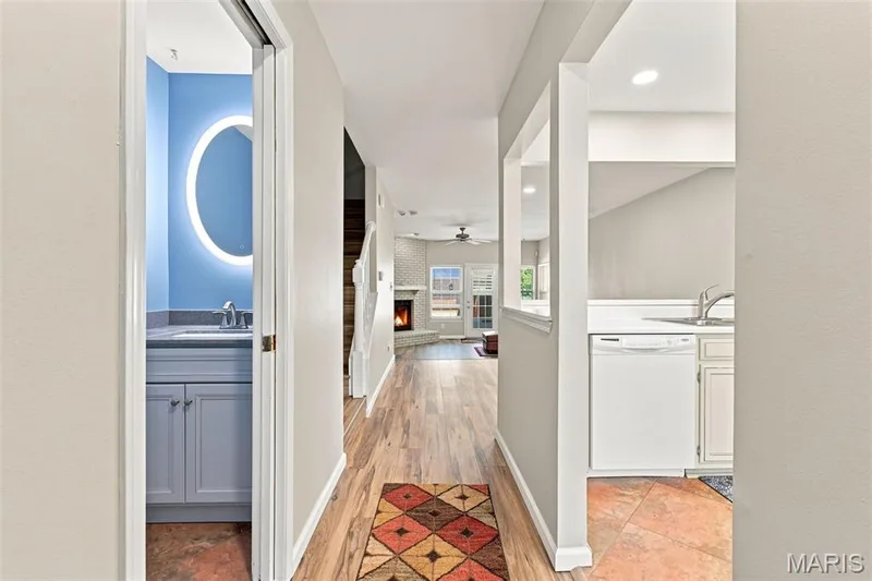 Wood-finish flooring throughout, with a recessed kitchen area featuring a stainless steel sink and white dishwasher — 16561 Carriage View Court, Wildwood, MO 63040