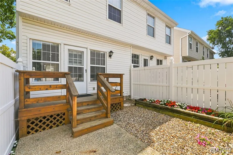 Private outdoor space featuring a wood deck, white privacy fencing, and a decorative flower bed — 16561 Carriage View Court, Wildwood, MO 63040