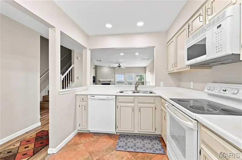 Kitchen with light cabinetry, white appliances, and a double basin sink — 16561 Carriage View Court, Wildwood, MO 63040