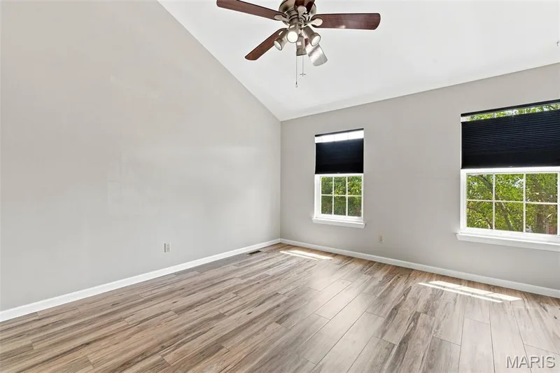 Vaulted ceiling with a ceiling fan light fixture, wood-finish flooring, and two windows — 16561 Carriage View Court, Wildwood, MO 63040