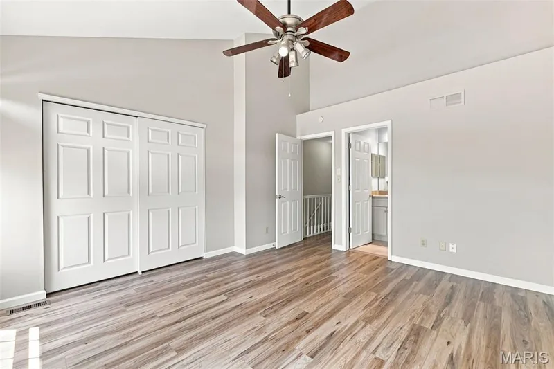Vaulted ceiling with a ceiling fan, wood-finish flooring, and white paneled bi-fold closet doors — 16561 Carriage View Court, Wildwood, MO 63040